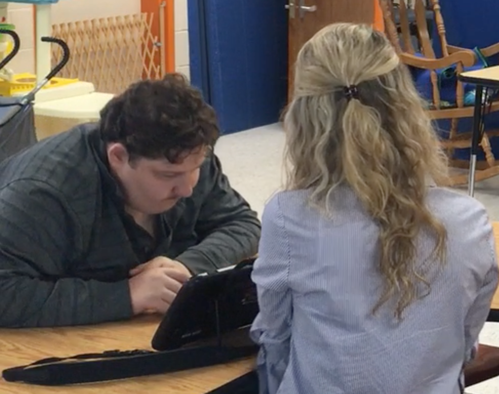 teacher and student reading together at a table